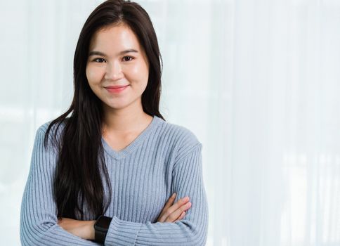 Close up headshot portrait young Asian happy beautiful woman healthy smiling face long hair stand crossed arm, studio shot looking to camera at home and have a copy space