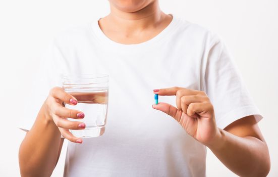 Closeup young Asian woman hold pill drugs in hand ready take medicines with a glass of water, studio shot isolated on white background, Healthcare and medical pharmacy concept