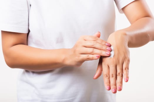 Closeup young Asian woman applying lotion cosmetic moisturizer cream on her behind the palm skin hand, studio shot isolated on white background, Healthcare medical and hygiene skin body care concept