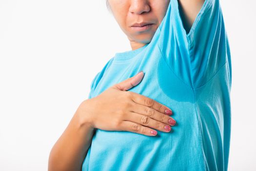 Closeup young Asian young woman hyperhidrosis sweating. Female very badly have armpit sweat stain on her clothes, studio shot isolated on white background, Healthcare medical concept