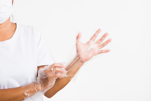 Woman hand wearing single use protect disposable transparent plastic glove, studio shot isolated on white background