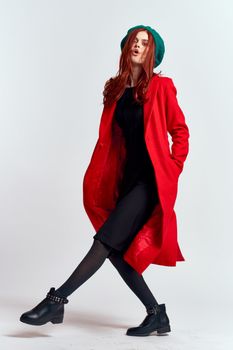 emotional woman in a red coat and with a hat in full growth on a light background black boots pose model. High quality photo