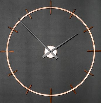 Round industrial wall clock in brass on a granite black background.