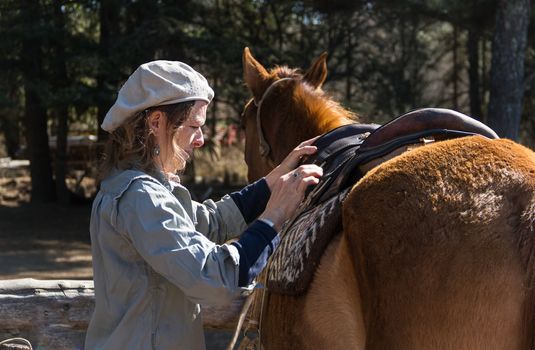 rural woman saddling her horse in the field