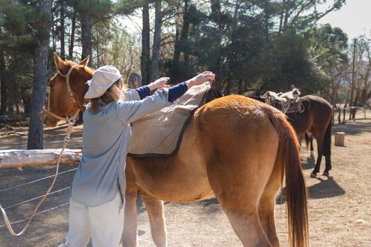 rural woman saddling her horse in the field