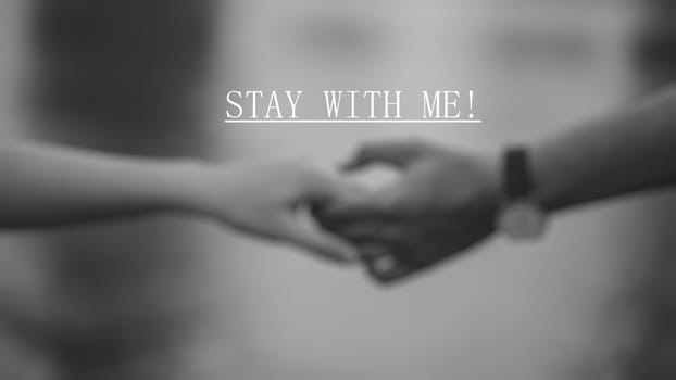 "Stay with me" inspirational text with holding hands blurred background.