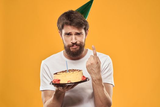 A bearded man with a cake and in a cap celebrating his birthday. High quality photo