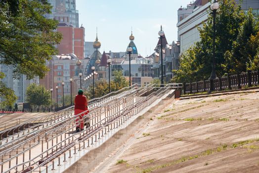 Kiev / Ukraine - September 10, 2020 - A woman climbs a long metal ramp for handicapped people, bicycles and people with strollers, near Natalka Park in the Obolon district of Kiev, Ukraine.