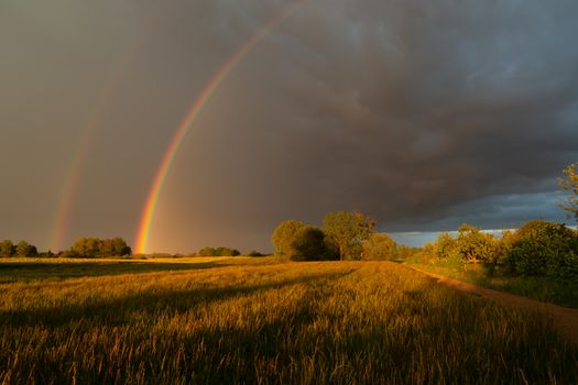 A double rainbow against the background of stormy clouds, summer view