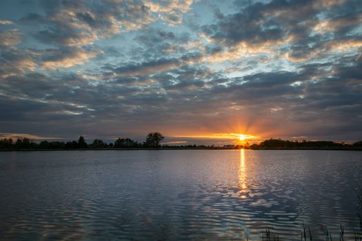 Beautiful sunset with clouds over the lake, spring evening