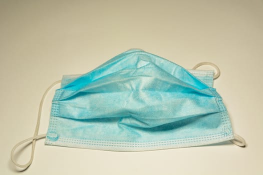 Worn out surgical mask blue colour, light background
