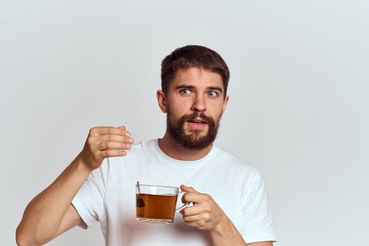 man with a cup of tea in a bag on a light background Hot drink cropped view model. High quality photo