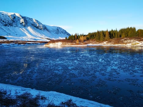 Iceland's breathtaking winter landscapes. River with pieces of ice on the background of mountains.