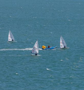 Portland harbour, United Kingdom - July 2, 2020: High Angle aerial portrait format shot of the laser class sailing racing dinghies and a rescue boat in Portland harbour.