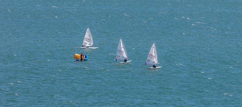 Portland harbour, United Kingdom - July 2, 2020: High Angle aerial panoramic shot of the laser class sailing racing dinghies and a rescue boat in Portland harbour.