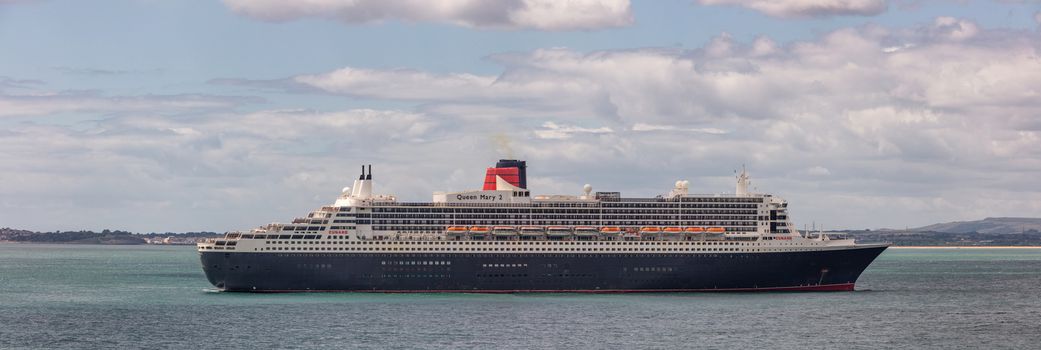 Weymouth Bay, United Kingdom - July 6, 2020: Beautiful panoramic shot of Cunard cruise ship Queen Mary 2 anchored in Weymouth Bay.