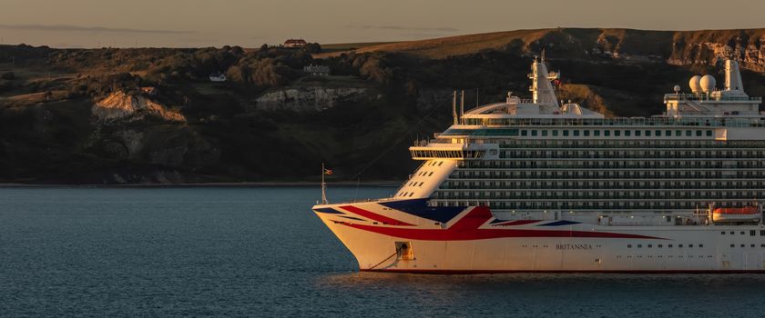 Weymouth Bay, United Kingdom - July 6, 2020: Beautiful panoramic shot of P&O cruise ship Britannia anchored in Weymouth Bay at sunset.