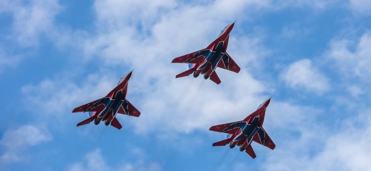 Barnaul, Russia - September 18, 2020: A low angle close-up shot of Strizhi MiG-29 jet squadron performing stunts during an aeroshow. Blue cloudy sky as a background.