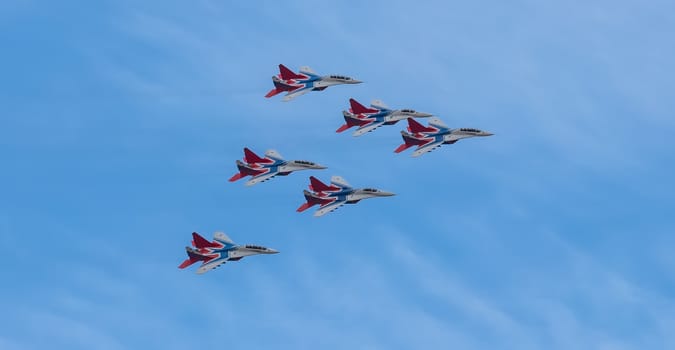 Barnaul, Russia - September 18, 2020: A low angle shot of Strizhi MiG-29 fighter jet squadron performing stunts during an aeroshow. Blue cloudy sky as a background.