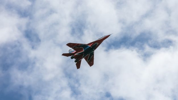 Barnaul, Russia - September 18, 2020: A low angle close-up shot of Strizhi MiG-29 fighter jet performing stunts during an aeroshow. Blue cloudy sky as a background.