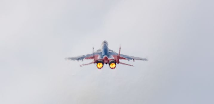 Barnaul, Russia - September 19, 2020: A low angle close-up shot of Strizhi MiG-29 fighter jet performing stunts during an aeroshow. Two jets heating up air and making it blurry around the plane.