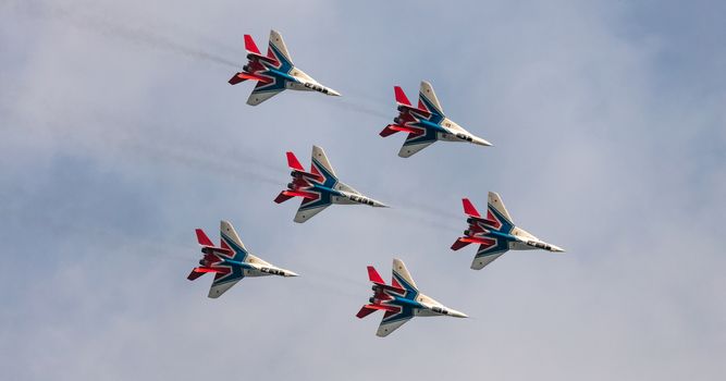 Barnaul, Russia - September 19, 2020: A shot of Strizhi MiG-29 fighter jet squadron performing stunts during an aeroshow. Blue cloudy sky as a background.