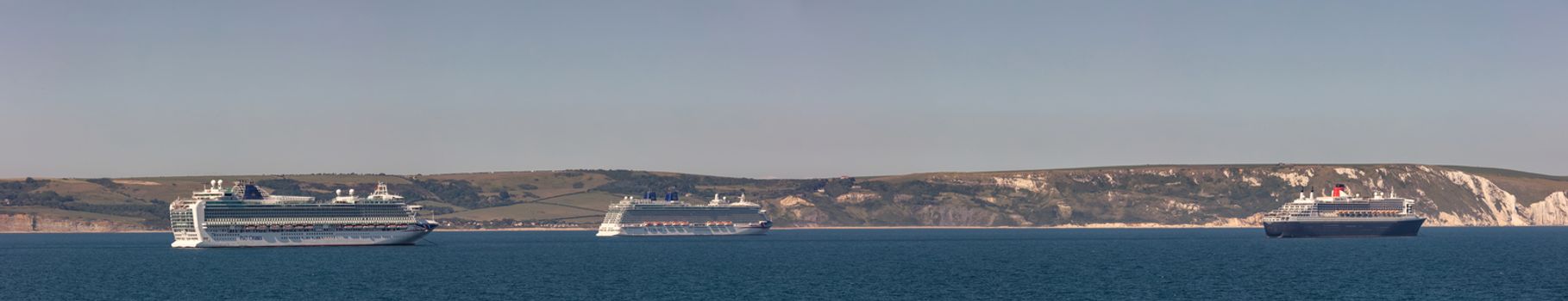 Weymouth Bay, United Kingdom - June 25, 2020: Beautiful panoramic shot of P&O cruise ships Azura and Britannia, Cunard cruise ship Queen Mary 2 anchored in Weymouth Bay.
