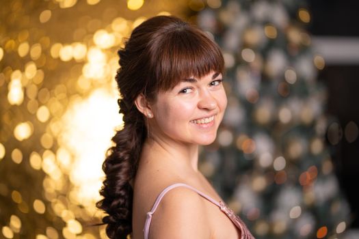 Stylish beautiful girl among sparkles and gerlands at a Christmas party.