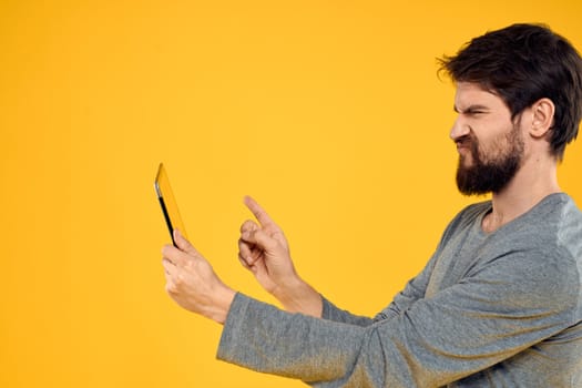 Bearded man with tablet in hands technology work wireless device yellow background. High quality photo