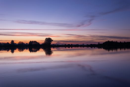 Clouds after sunset over a calm lake, October view