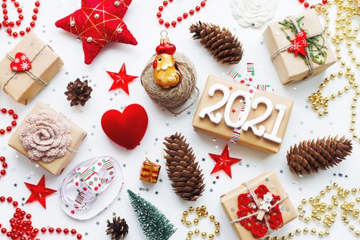 Christmas presents with decorations. New Year 2021 gifts in craft paper, pine cones, red hearts and confetti. Flay lay, top view background.