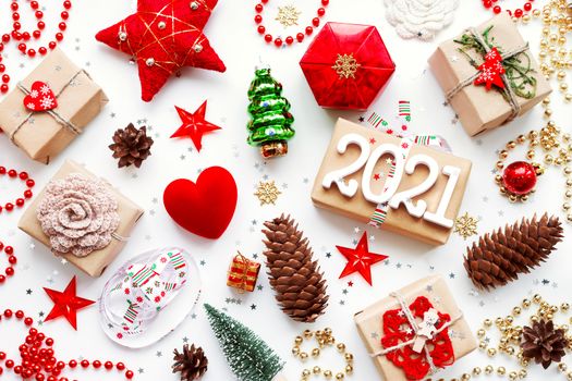 Christmas presents with decorations. New Year 2021 gifts in craft paper, pine cones, red hearts and confetti. Flay lay, top view background.