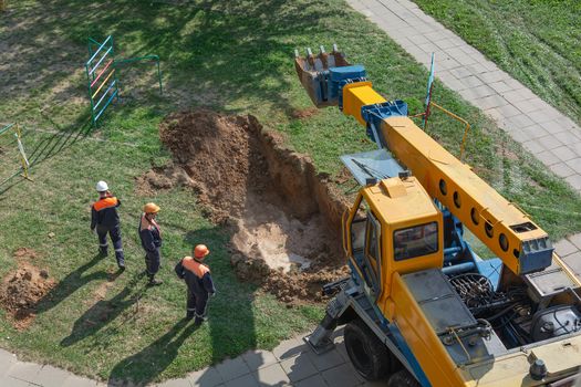 Minsk, Belarus - 11 September 2018: a team of workers and an excavator repair a burst heating main
