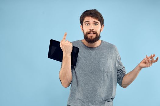 Emotional man with a tablet in the hands of a wireless device internet technology lifestyle blue background. High quality photo