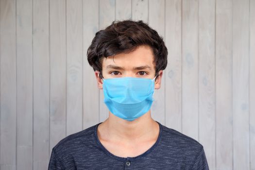 Portrait of young man wearing disposable mask during coronavirus contagious disease. Covid-19 and teens, coronavirus outbreak. Personal protection against coronavirus, virus. Looking into the camera