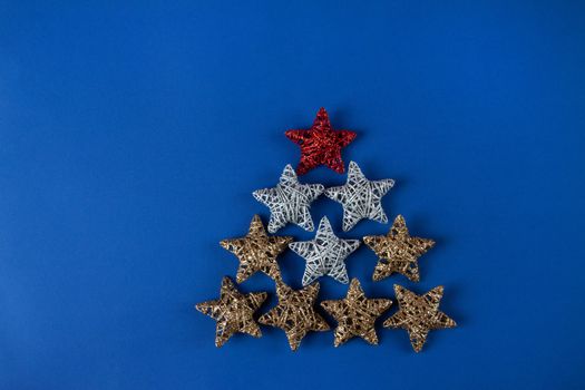 Brilliant red, gold, silver Christmas star on blue background. Use for New Year's greetings. Minimal banner, copy space for text, flatlay.