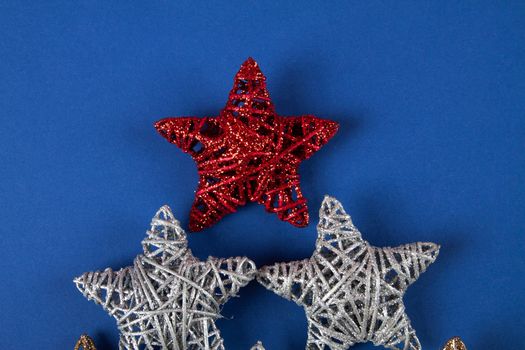 Brilliant red, gold, silver Christmas star on blue background. Use for New Year's greetings. Minimal banner, copy space for text, flatlay.