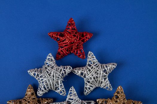 Brilliant red, gold, silver Christmas star on blue background. Use for New Year's greetings. Minimal banner, copy space for text, flatlay.