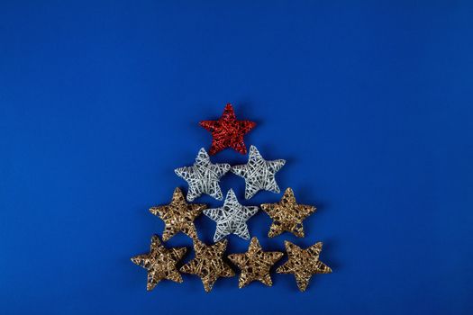 Brilliant red, gold, silver Christmas star on blue background. Use for New Year's greetings. Minimal banner, copy space for text, flatlay.