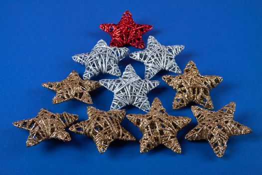 Brilliant red, gold, silver Christmas star on blue background. Use for New Year's greetings. Minimal banner, copy space for text, flatlay.