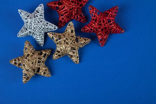 Brilliant red, gold, silver Christmas star on blue background. Use for New Year's greetings. Minimal banner, copy space for text, flatlay.