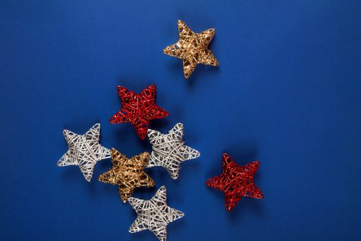 Brilliant red, gold, silver Christmas star on blue background. Use for New Year's greetings. Minimal banner, copy space for text, flatlay.