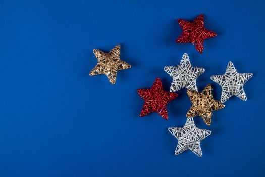 Brilliant red, gold, silver Christmas star on blue background. Use for New Year's greetings. Minimal banner, copy space for text, flatlay.