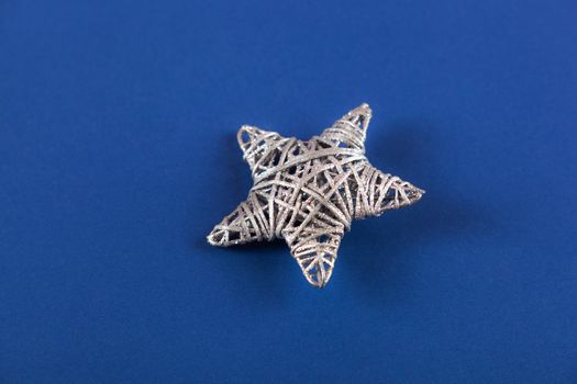 Brilliant silver Christmas star on blue background. Use for New Year's greetings. Minimal banner, copy space for text, flatlay.