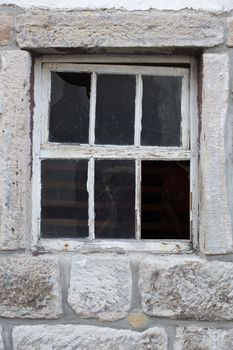 Old weathered window in a massive stone wall