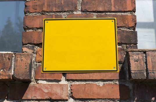 Yellow metal blank signboard on an old brick wall