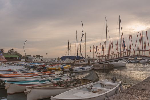 Boats docked in a harbor under the sunset sky, lake landscape with warm light