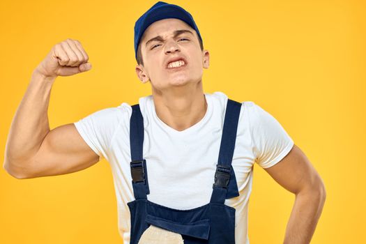 Working man in uniform of gloves rendering service yellow background. High quality photo