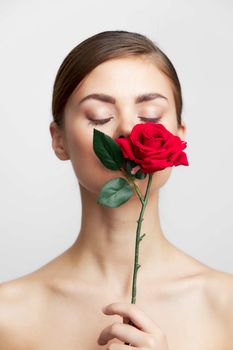 Woman with flower with closed eyes sniffing a rose charm close-up
