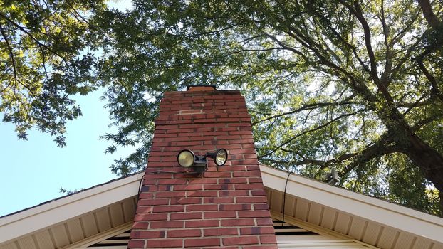 red chimney bricks or masonry and flood light on house with tree